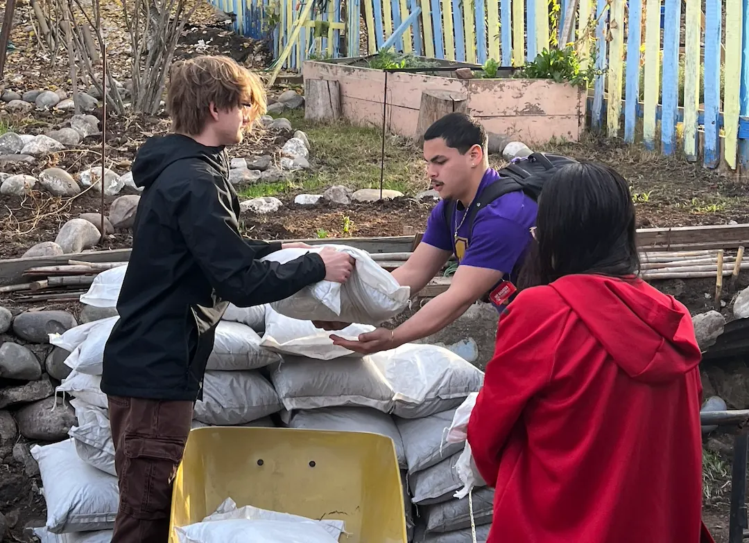 Voluntarios trasladando sacos de tierra para el huerto